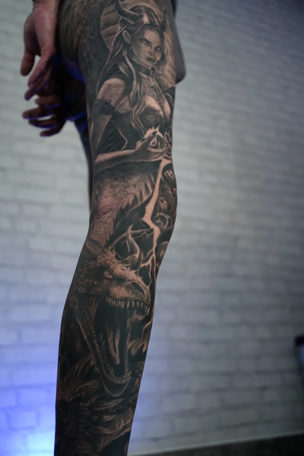 Black and grey fantasy leg tattoo with dragon and horned woman detail