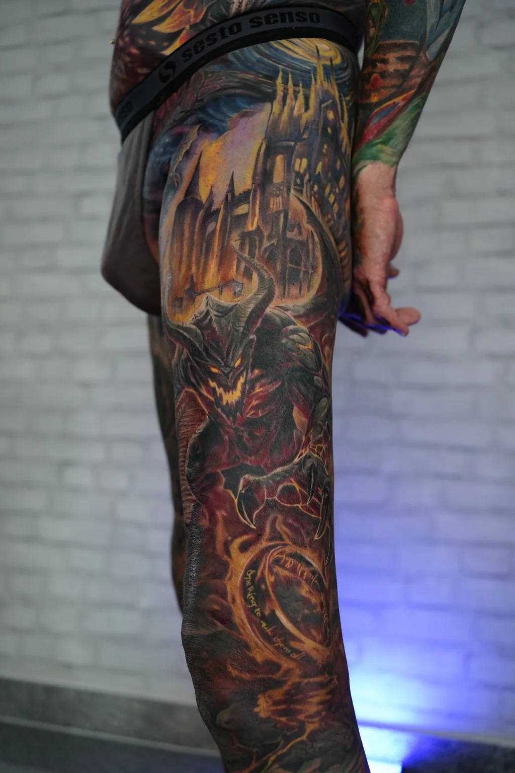 Color fantasy leg tattoo with dark fortress and fire creature detail